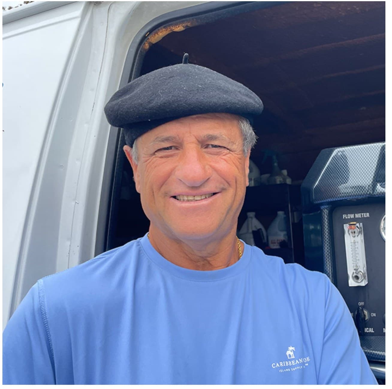 Peter De Leon, owner of After Effects Carpet Cleaning, smiling at the back of his work van with the truck-mounted flow meter behind him