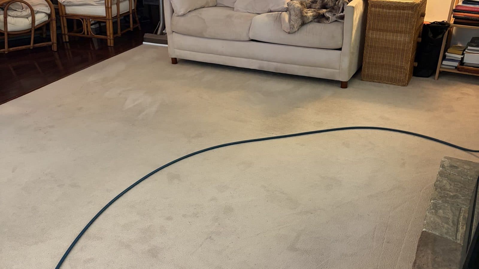 How to prepare for carpet cleaning: an Ocean County living room on arrival with the sofa still in place and the truck-mount hose already run across the beige carpet