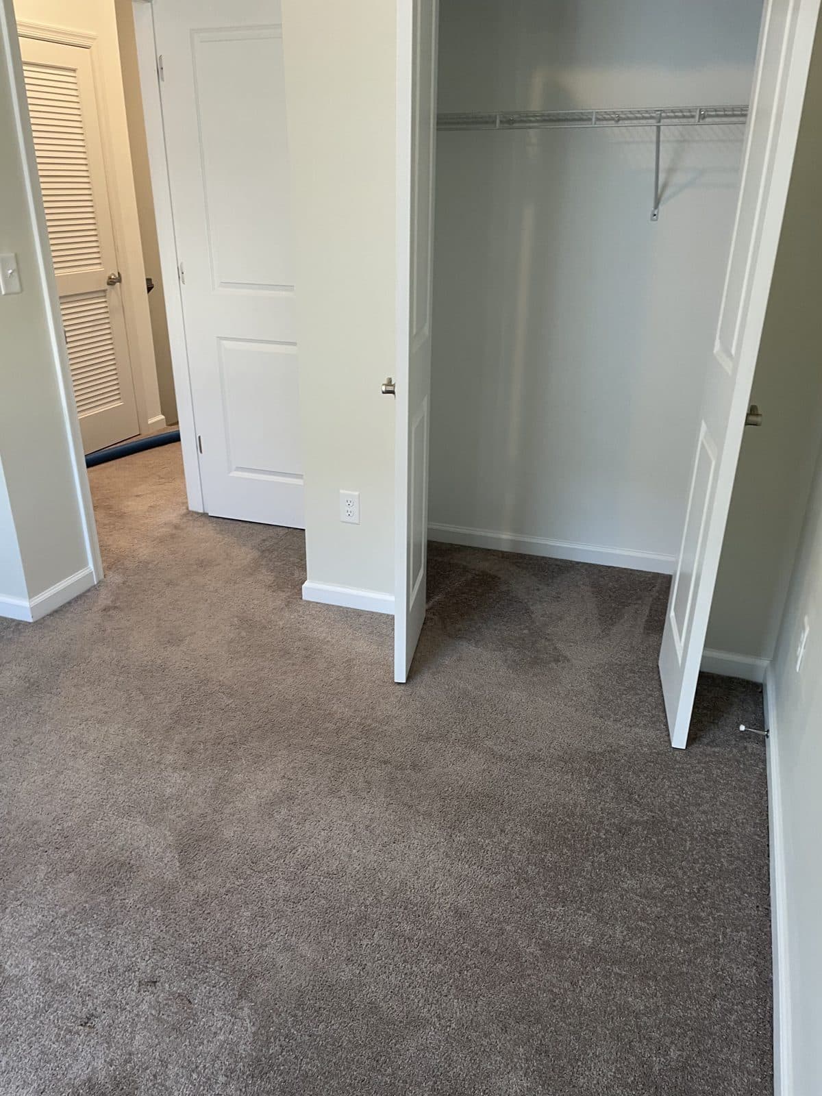 Plush neutral carpet freshly laid in an empty bedroom with the closet doors open